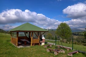 Drewniana altana z grillem, miejsce na ognisko i panorama gór — strefa relaksu przy domkach pod Muńcołem.