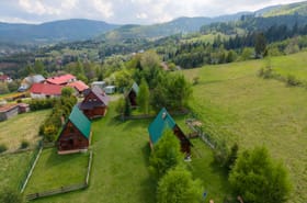 Widok z drona na całoroczne domki pod Muńcołem w Soblówce — Beskid Żywiecki, zielone wzgórza i dolina.