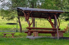 Rustykalna wiata piknikowa z ławkami na trawie — odpoczynek na świeżym powietrzu w Beskidach.